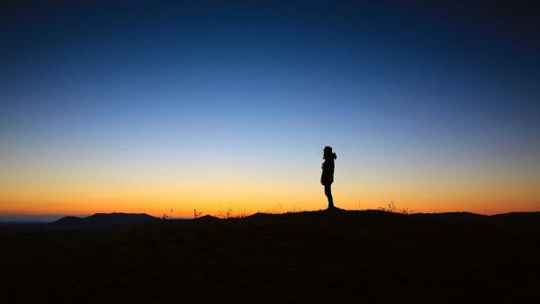 Man alone and introspective in rural setting with sunset and sky