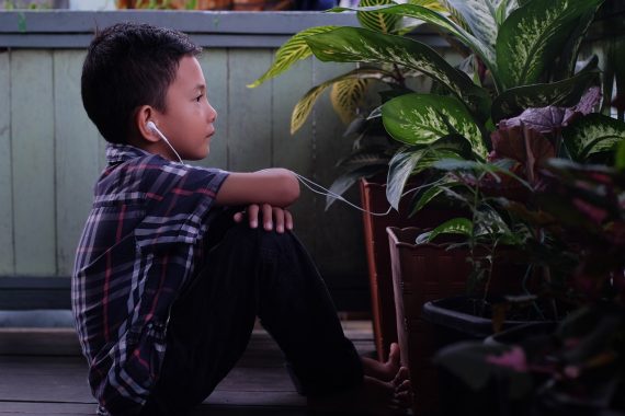 Child sitting on the floor with headphones on to represent autism and spread autism awareness