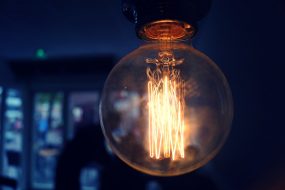 Lightbulb in darkened room with glowing filaments to symbolise brain and thinking processes