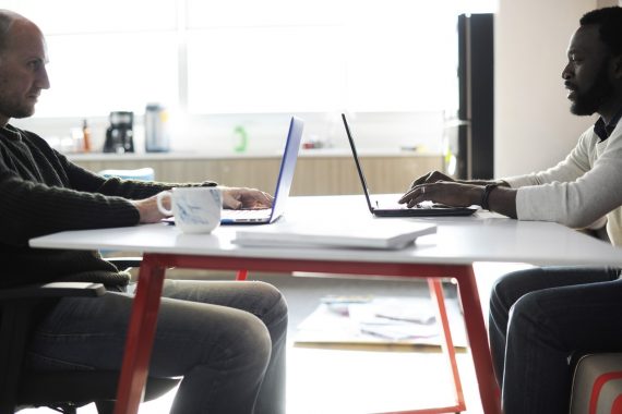 Colleagues at work with laptops facing each other