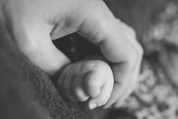 Mother clutching baby's hand in monochrome photo suggesting mother and child bond