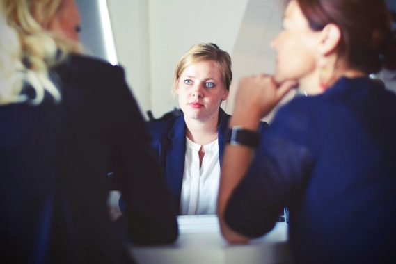 Disclosing a mental health issue in a meeting with two women talking across a table to another woman in smart business clothing