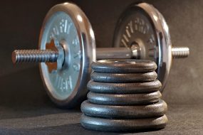 Weights on a bar at the gym and in a pile in the foreground