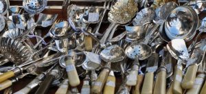 Antique silver spoons lined up for sale in market to represent Spoon Theory of chronic illness