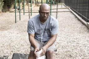 Man looking unhappy on swings in park, symbolising upset and low self-worth