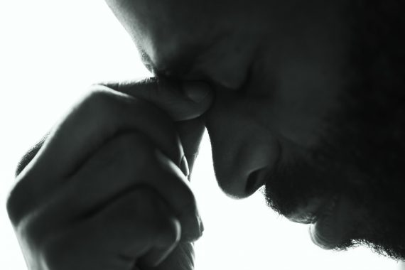 Man holding hand to forehead in pain and stress