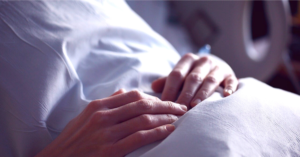 Hospital patient in bed with Long Covid - hands above bed cover