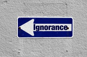 Facing ignorant GP described using Ignorance sign on white wall