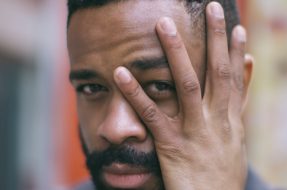 Man looking through his hand directly at camera showing eye movement and depicting EMDR blog post