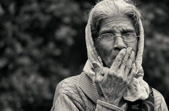 Elderly Asian lady with headscarf and glasses, wearing jumper